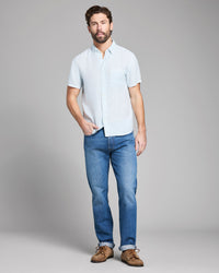 Man wearing a white shirt, blue jeans, and brown shoes on a gray background