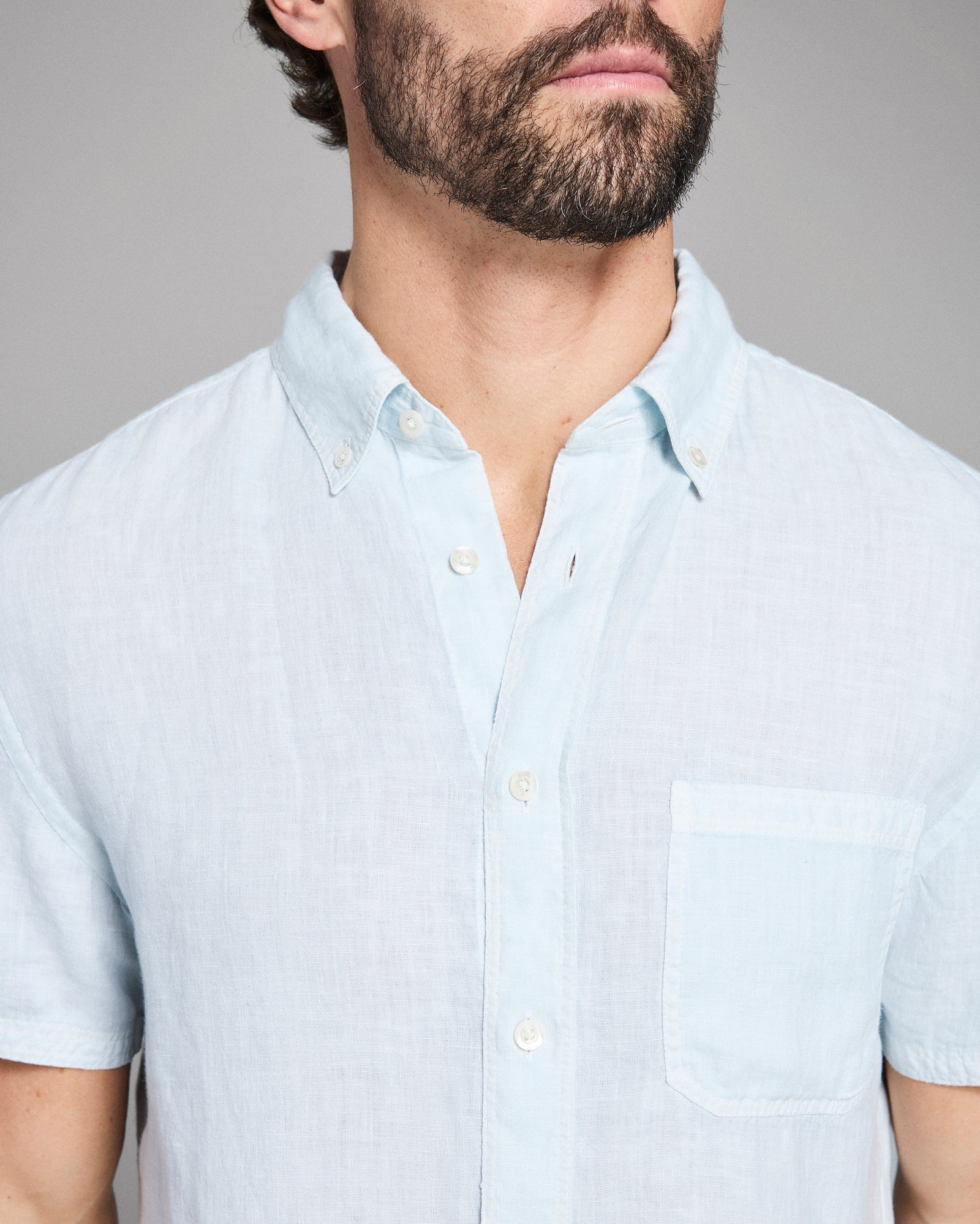 Man wearing a light blue short-sleeve shirt against a gray background