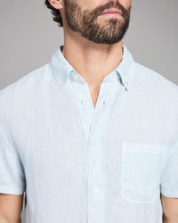 Man wearing a light blue short-sleeve shirt against a gray background