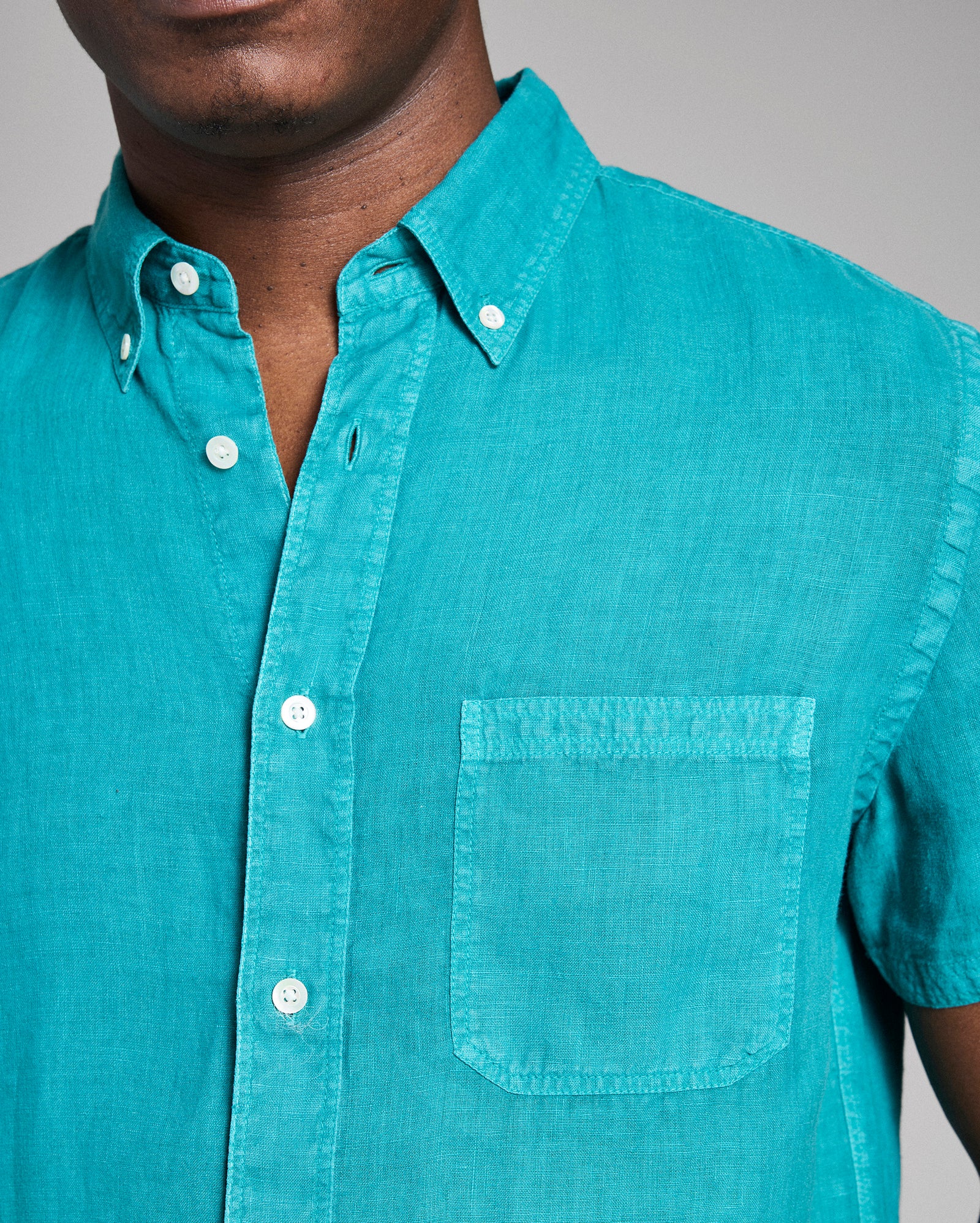 Teal button-up shirt worn by a person on a gray background
