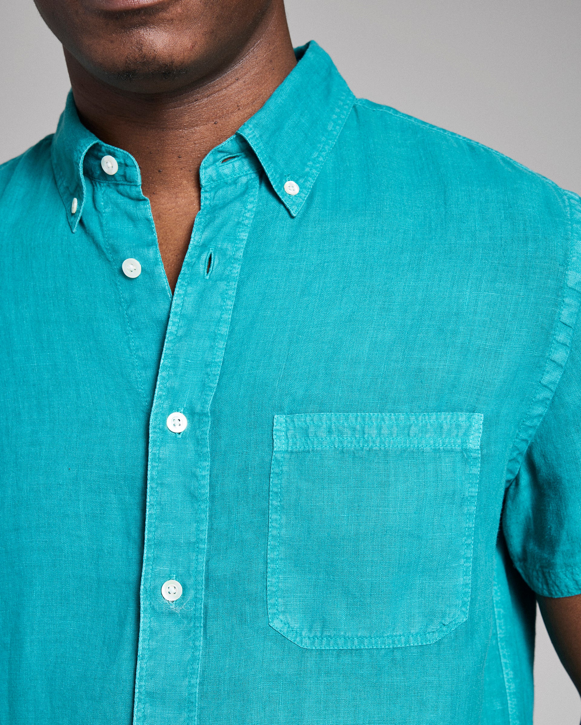 Teal button-up shirt worn by a person on a gray background