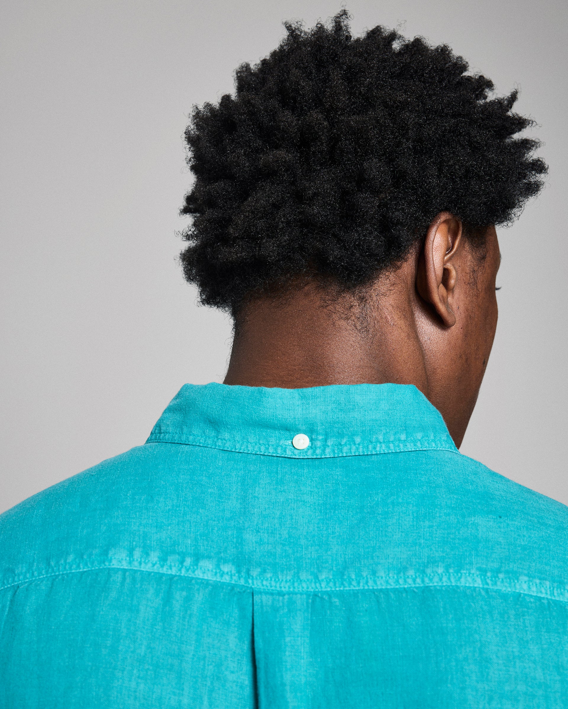 Person wearing a teal shirt with a gray background