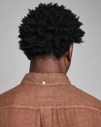 Person wearing a brown shirt with a plain background