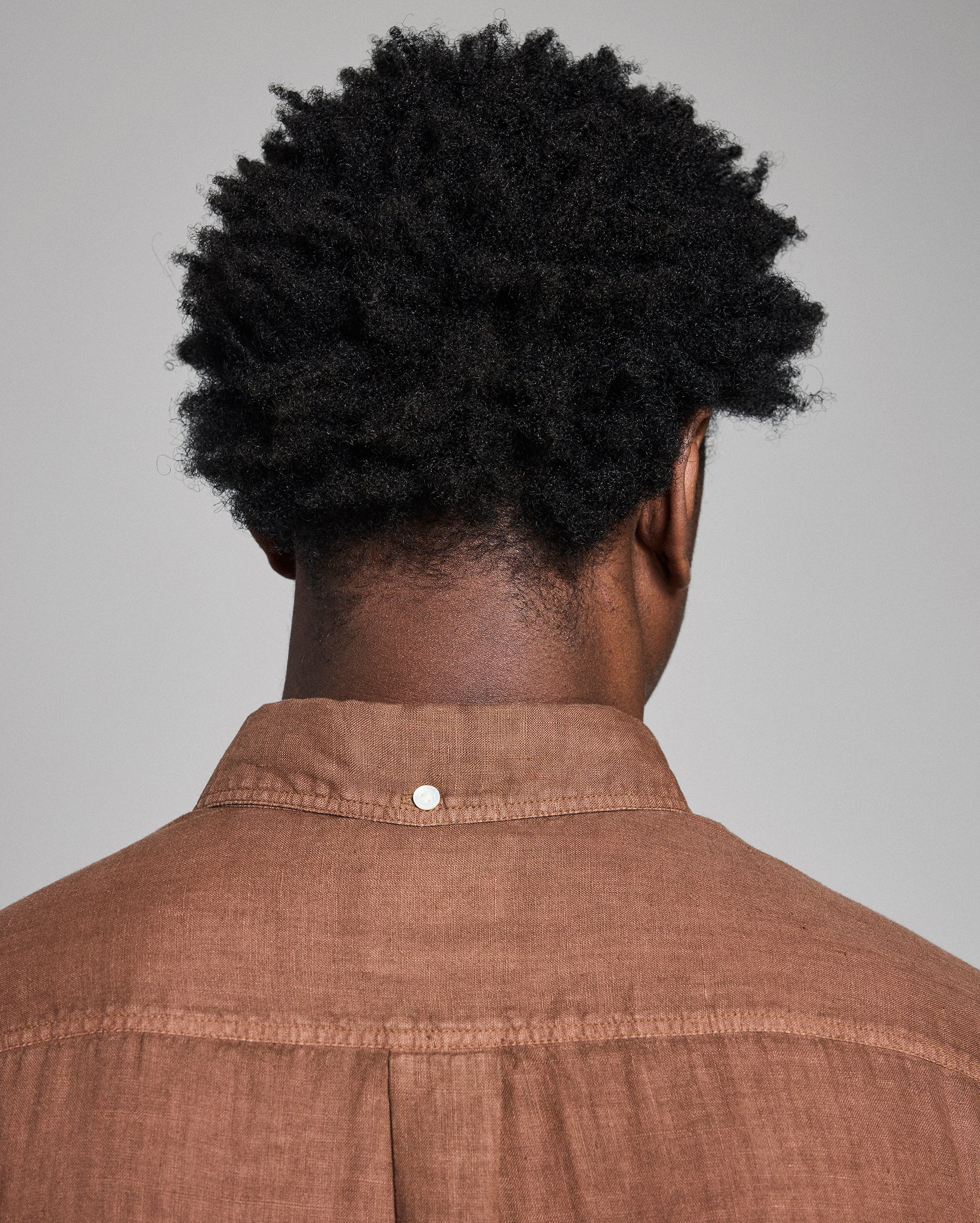 Person wearing a brown shirt with a plain background