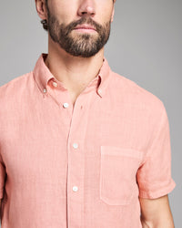 Man wearing a pink short-sleeve shirt against a gray background