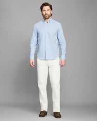 Man wearing a light blue shirt and white pants on a gray background
