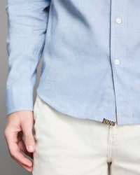 Light blue button-up shirt and beige pants on a neutral background