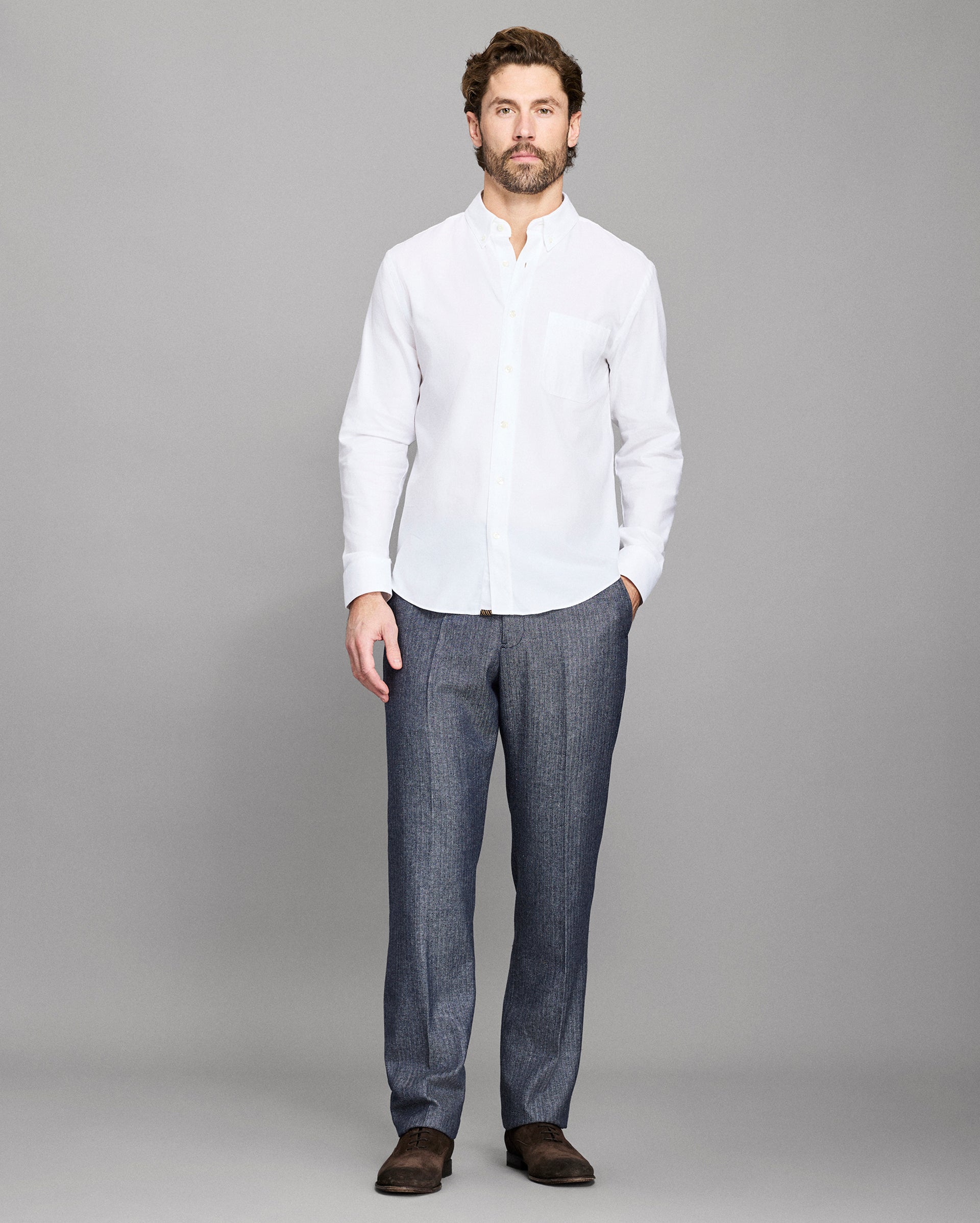 Man wearing a white shirt and gray pants on a gray background