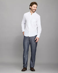 Man wearing a white shirt and dark pants against a gray background