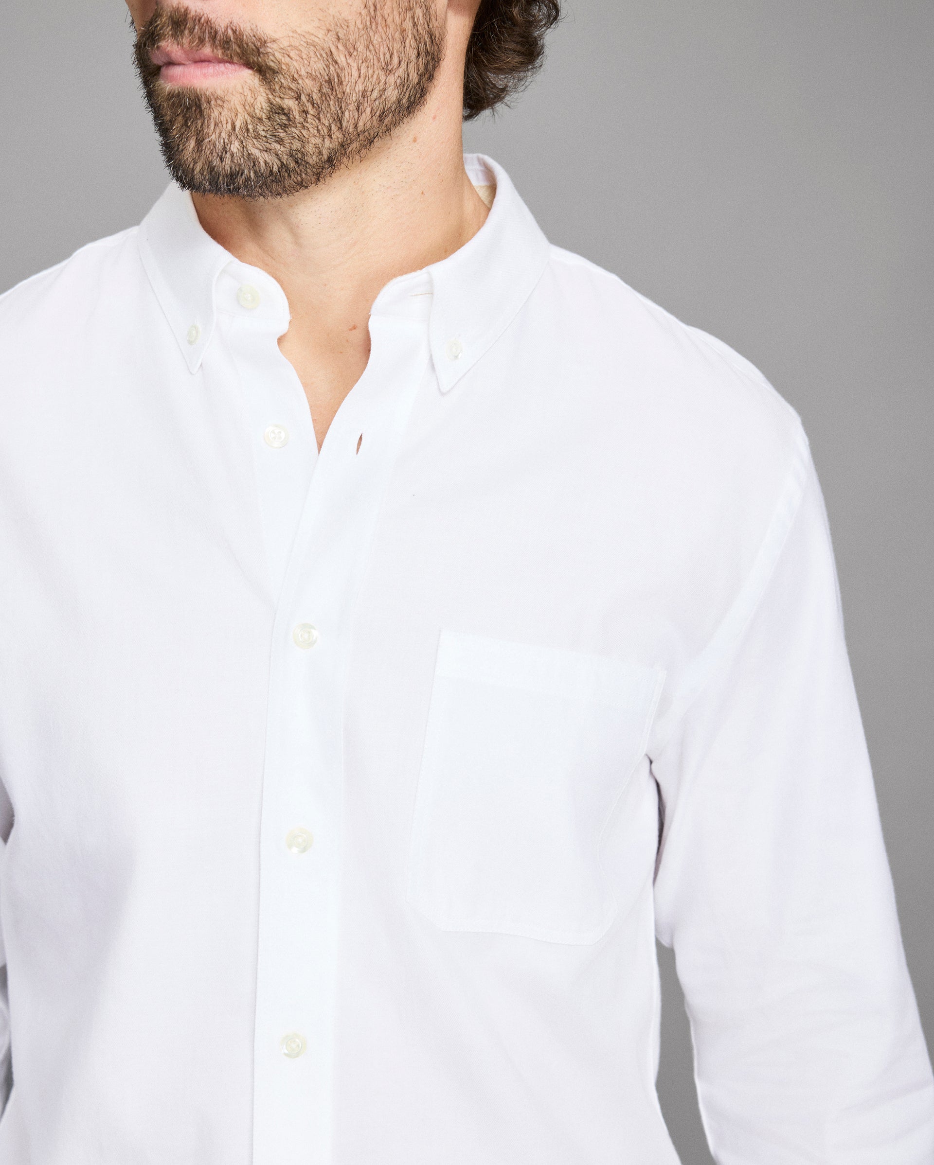Man wearing a white shirt against a gray background