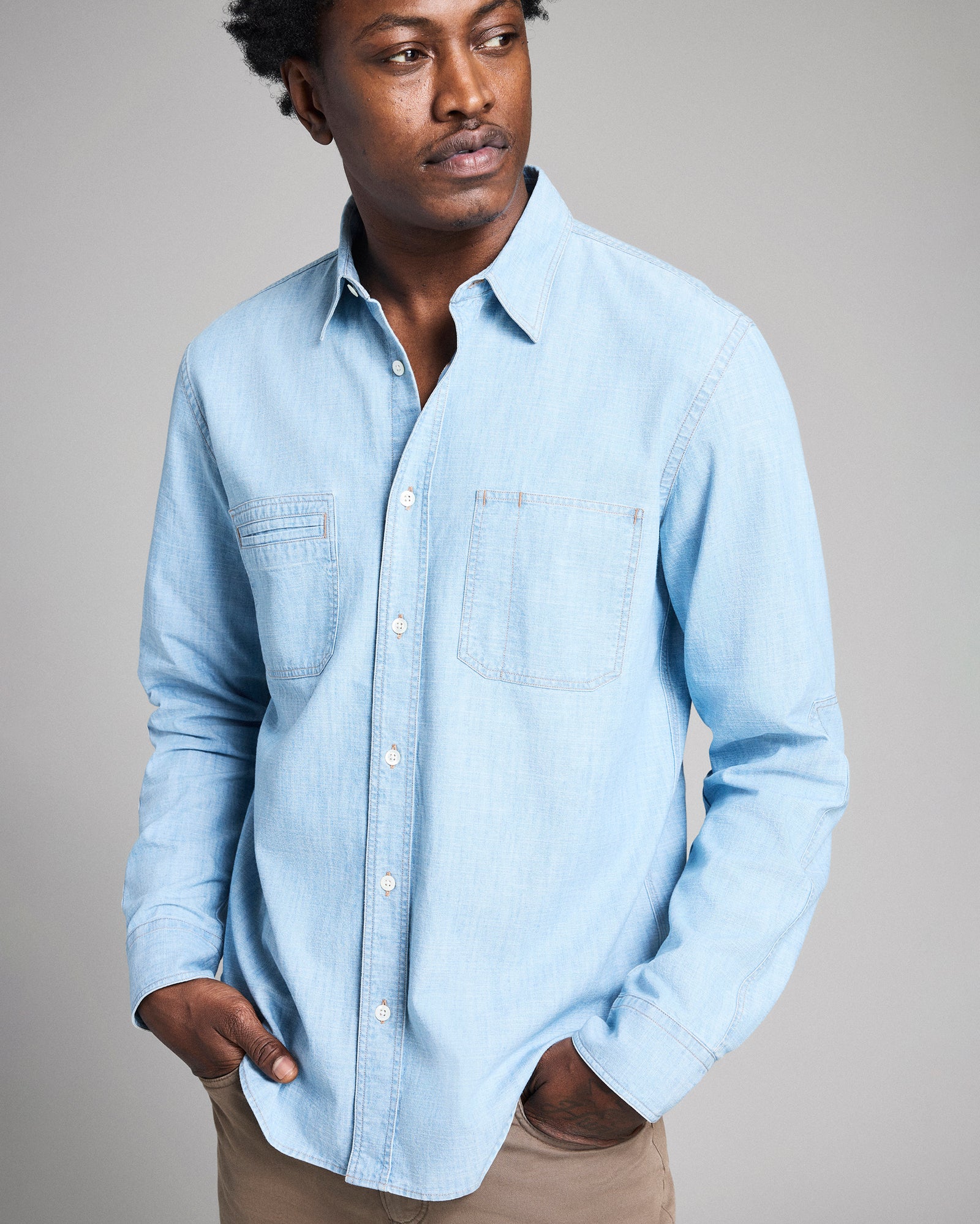 Man wearing a light blue denim shirt against a plain background