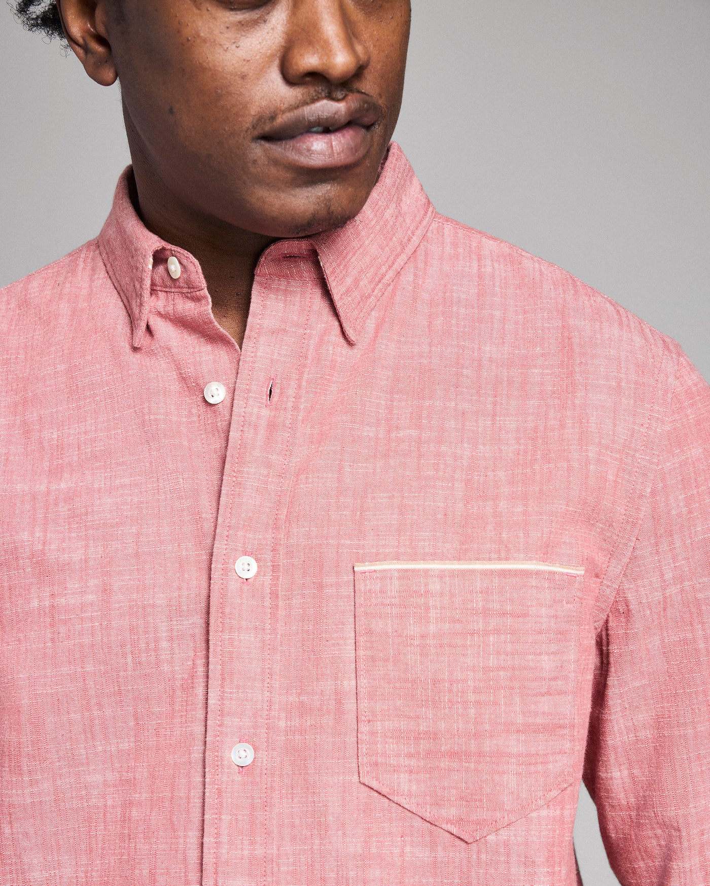 Man wearing a pink checkered shirt against a gray background