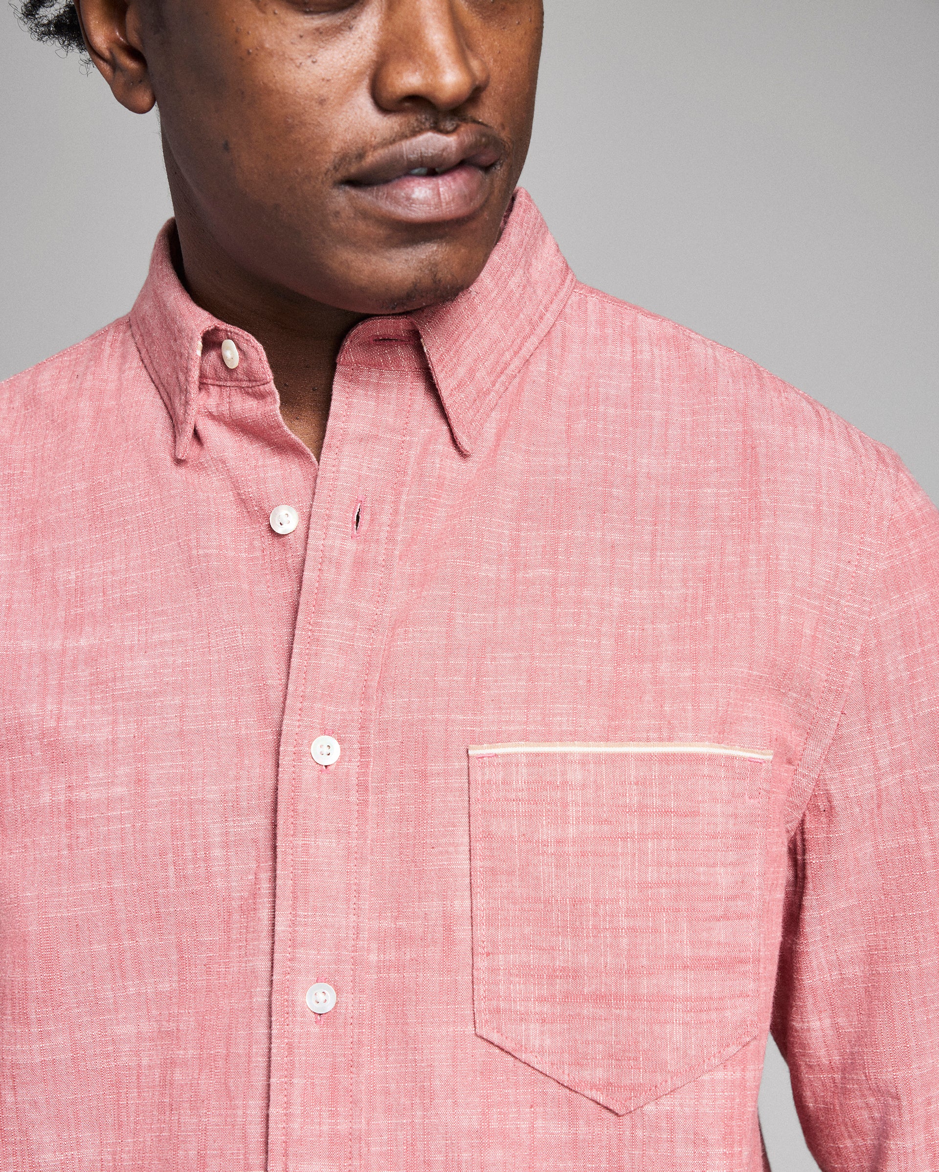 Man wearing a pink checkered shirt against a gray background