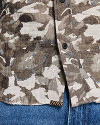 Camouflage jacket with button details on a blue denim background
