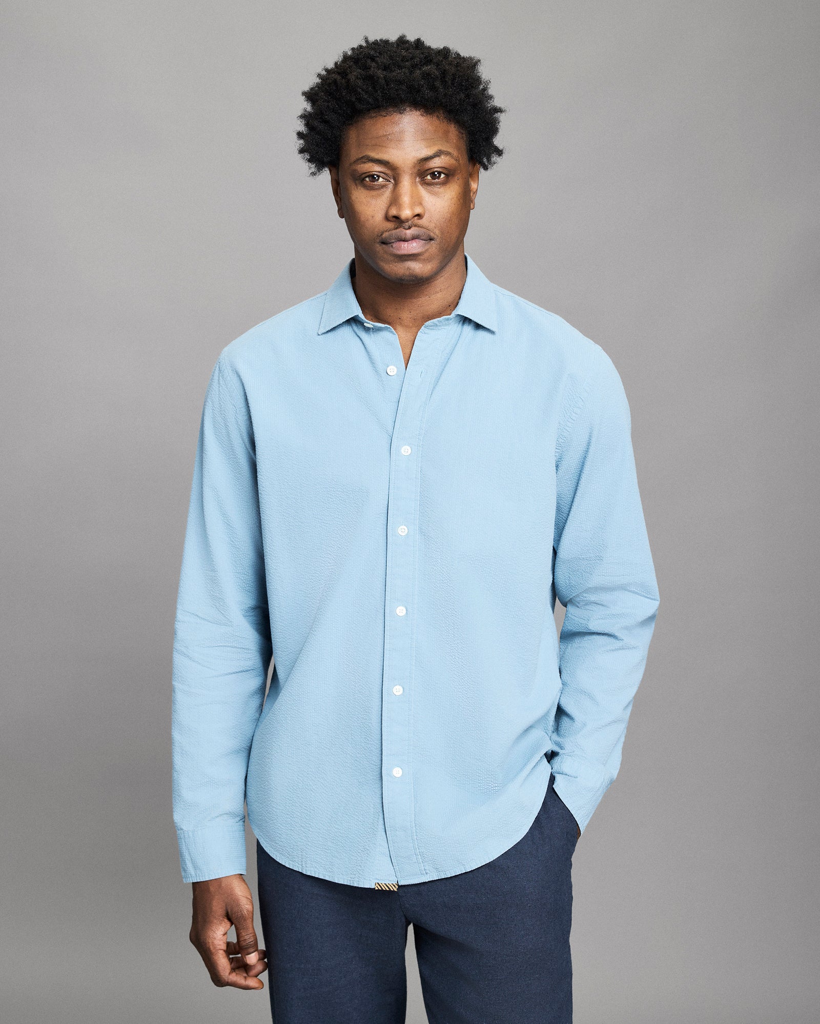 Man wearing a light blue shirt against a gray background