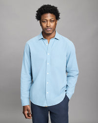 Man wearing a light blue shirt against a gray background