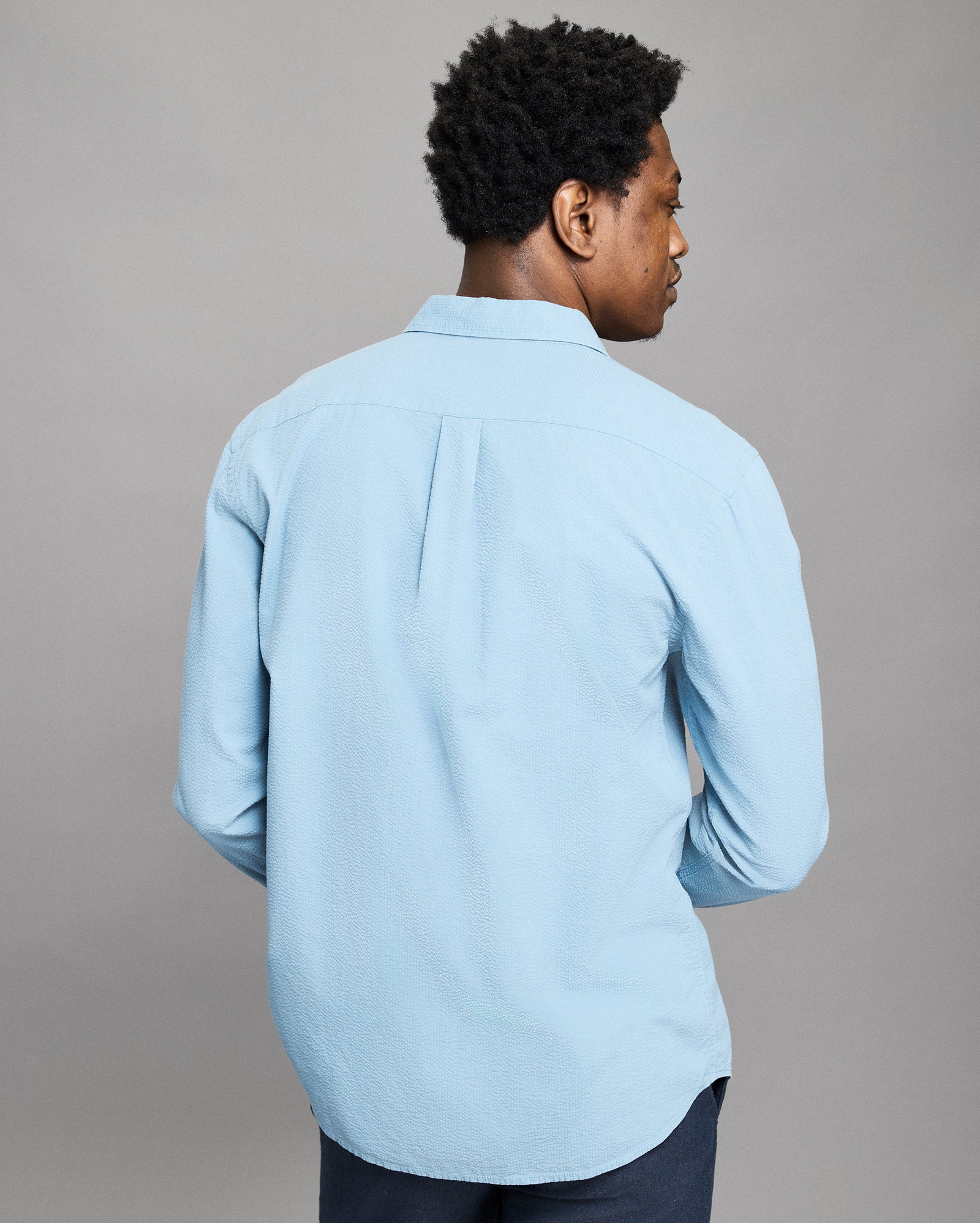 Person wearing a light blue shirt against a gray background