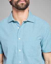 Man wearing a light blue checkered shirt against a gray background