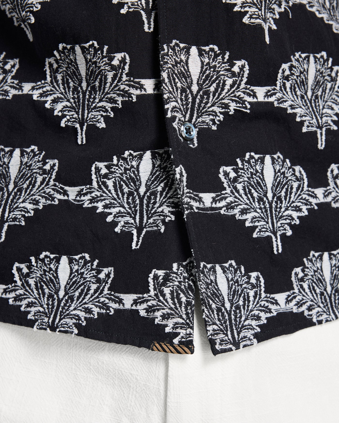 Close-up of black fabric with white leaf pattern on a white background