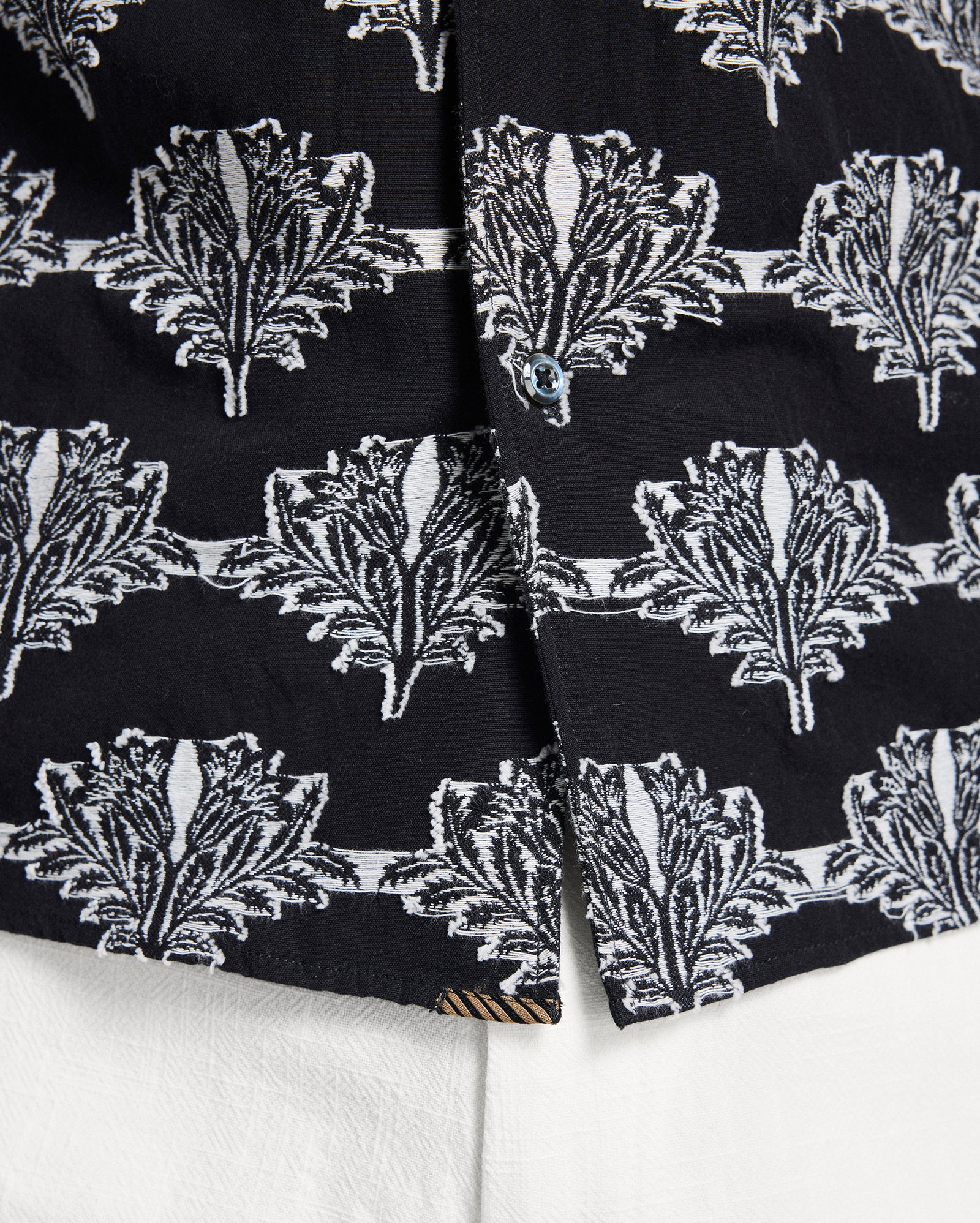 Close-up of black fabric with white leaf pattern on a white background