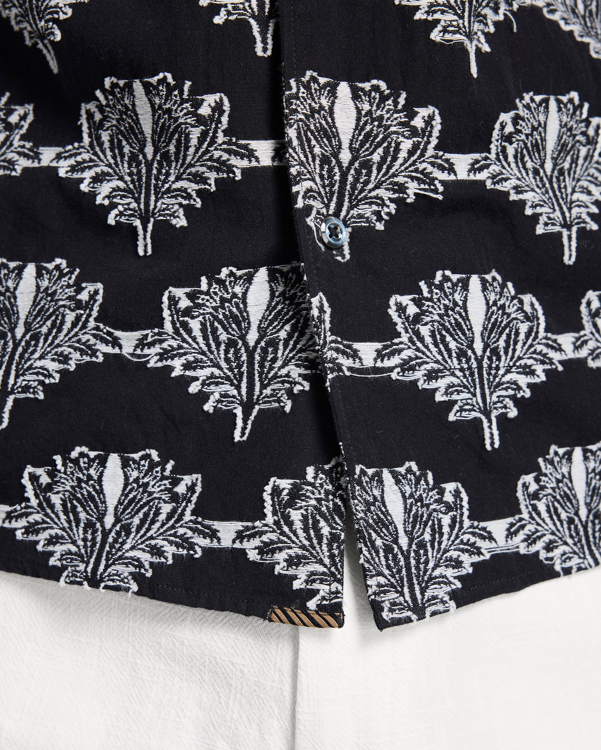 Close-up of black fabric with white leaf pattern on a white background