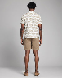 Man wearing a patterned shirt and beige shorts on a gray background