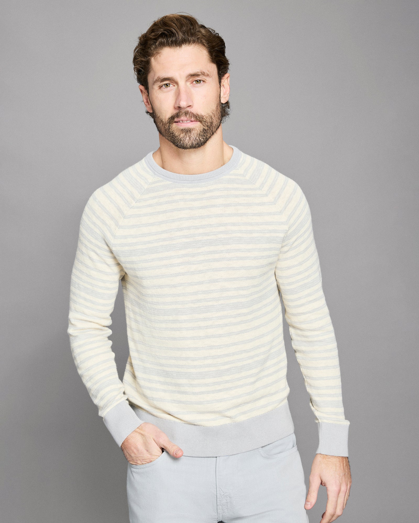 Man wearing a light-colored striped sweater against a gray background
