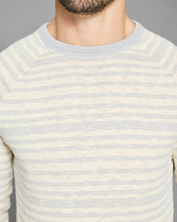 Close-up of a person wearing a light blue and white striped sweater against a gray background