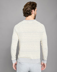 Man wearing a light-colored striped sweater against a gray background
