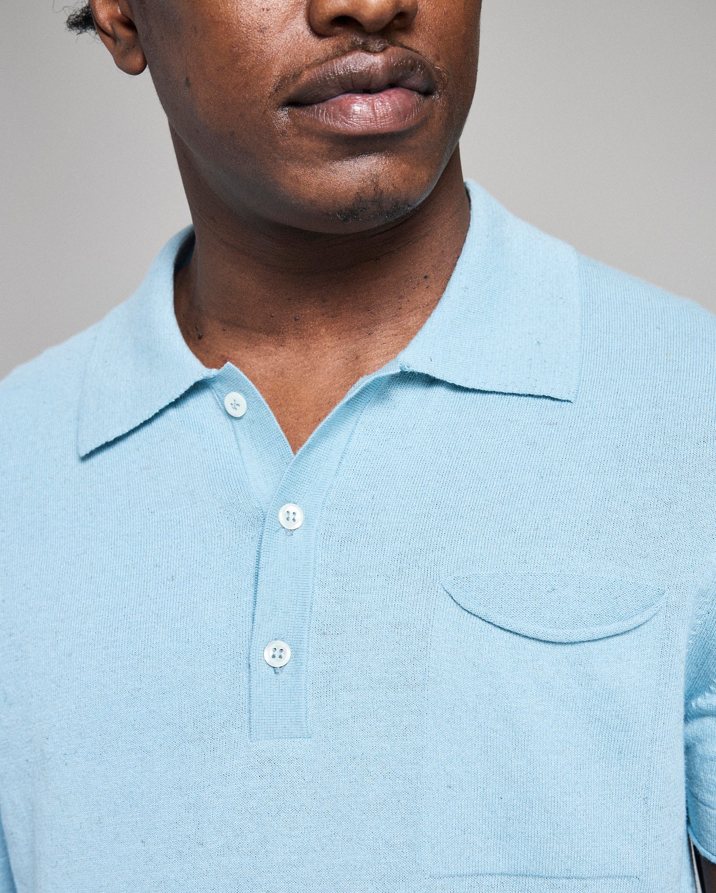 Man wearing a light blue polo shirt against a neutral background