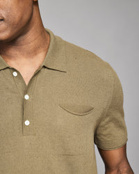 Man wearing a green polo shirt with a pocket on a gray background