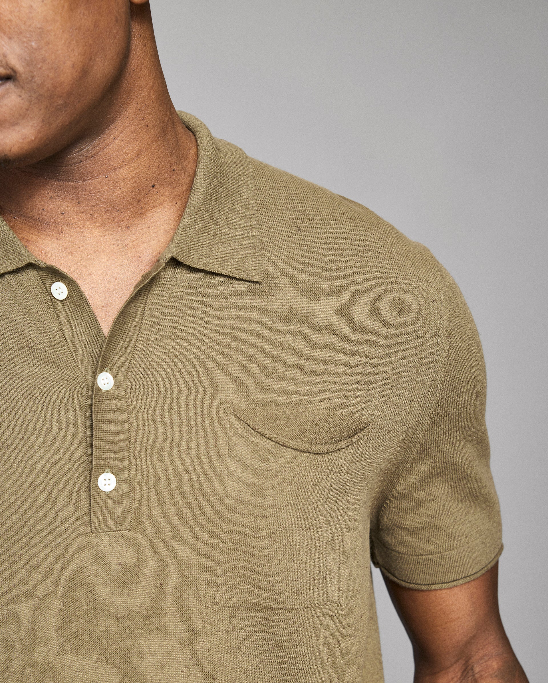 Man wearing a green polo shirt with a pocket on a gray background
