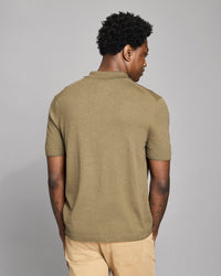 Man wearing a green polo shirt against a gray background