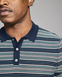 Man wearing a striped polo shirt with a neutral background