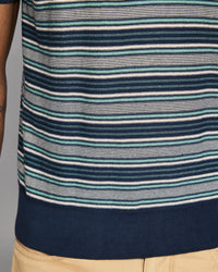 Close-up of a striped shirt with blue, green, and white horizontal lines on a gray background.