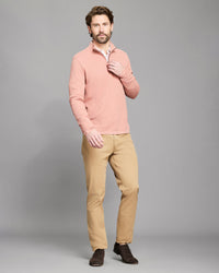 Model wears the textured half zip in salmon on a grey background.