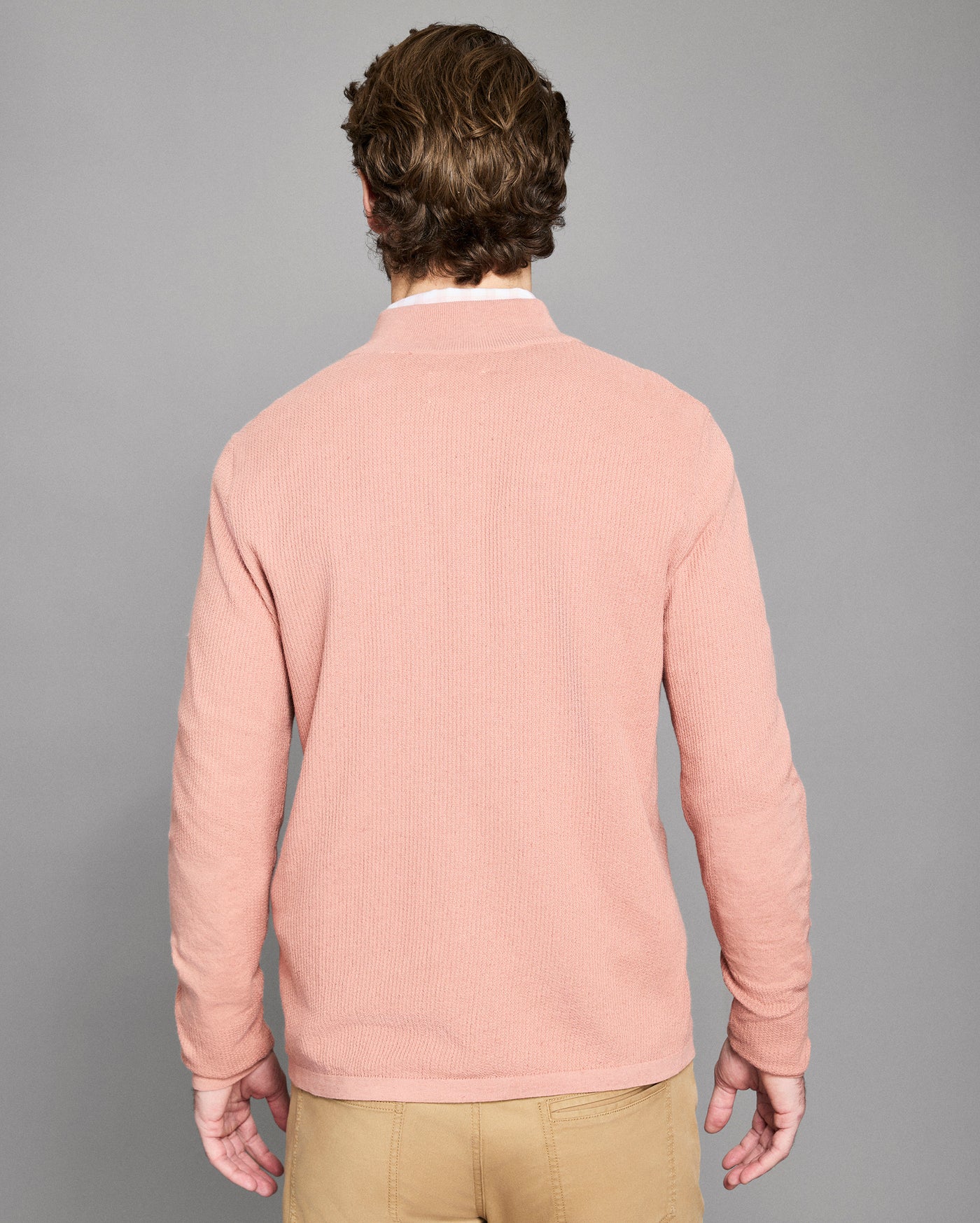 Man wearing a pink sweater against a gray background
