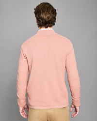 Man wearing a pink sweater against a gray background