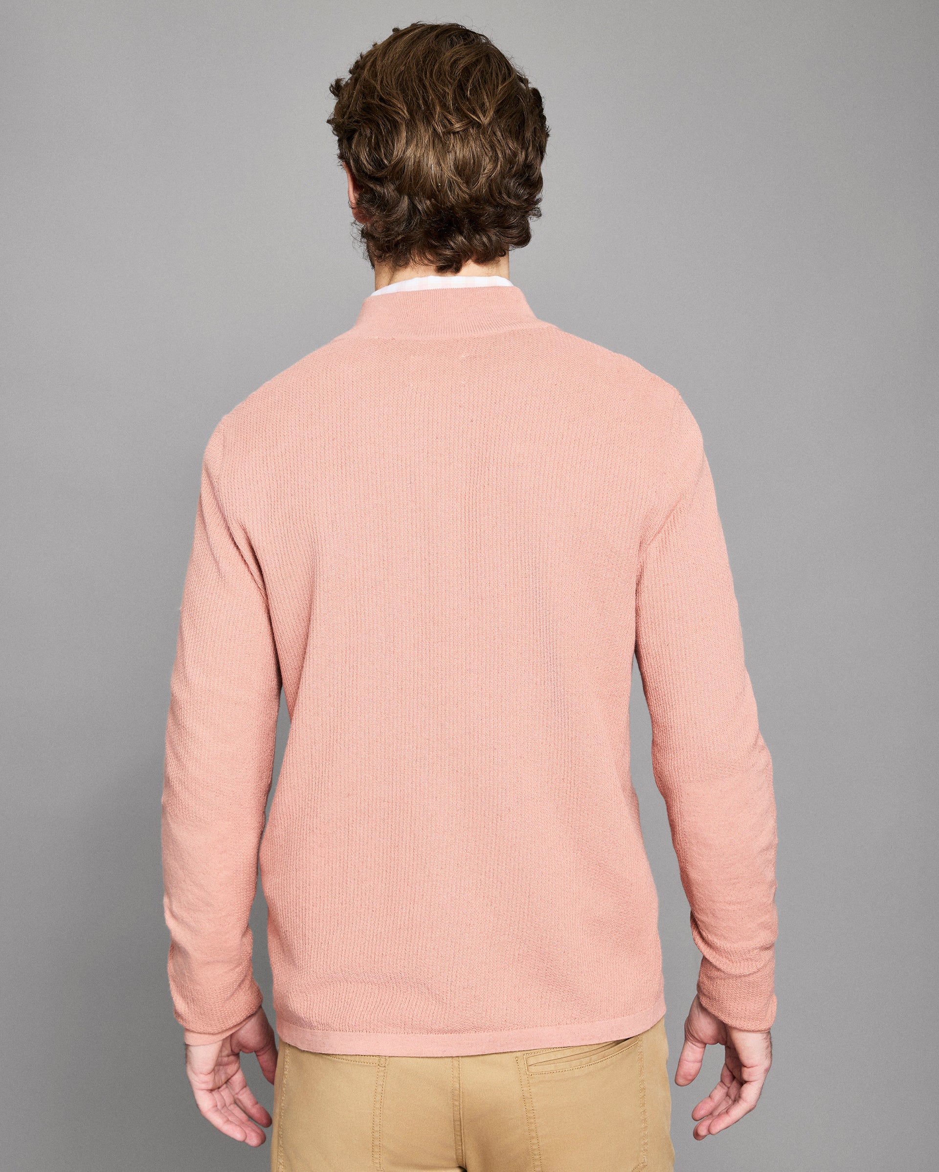 Man wearing a pink sweater against a gray background