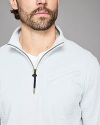Man wearing a light gray zip-up sweatshirt against a gray background