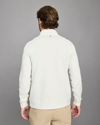 Man wearing a white sweater against a gray background
