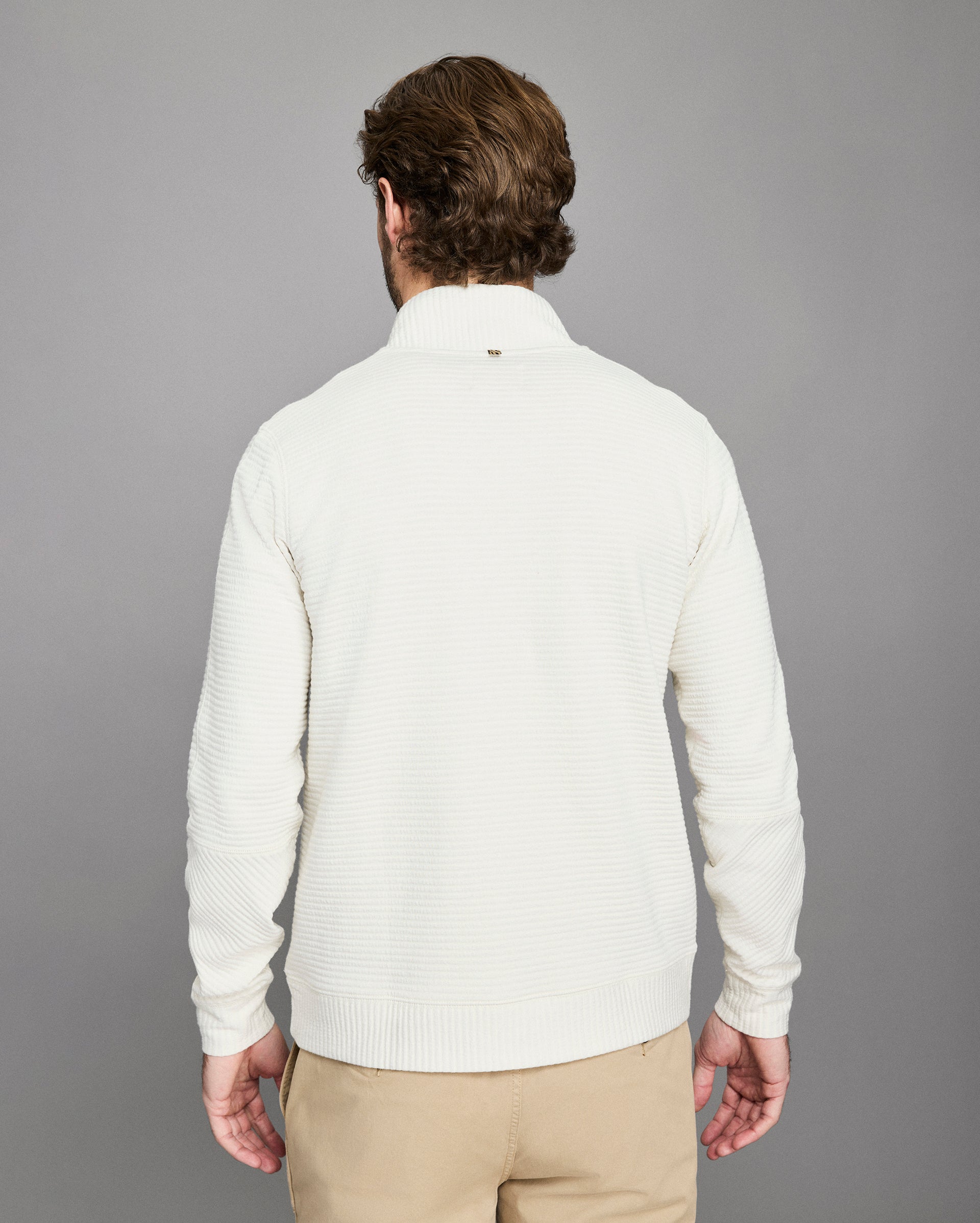 Man wearing a white sweater against a gray background