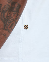 Close-up of a white shirt with a small black and gold logo on a white background