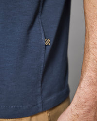 Close-up of a person wearing a navy blue shirt with a small logo on the chest.