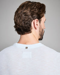 Man with styled hair and beard wearing a light gray shirt against a plain background