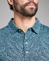 Man wearing a blue patterned shirt against a gray background