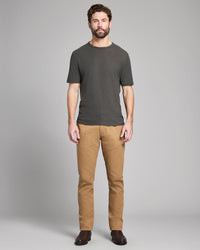 Man wearing a dark gray t-shirt and tan pants on a gray background