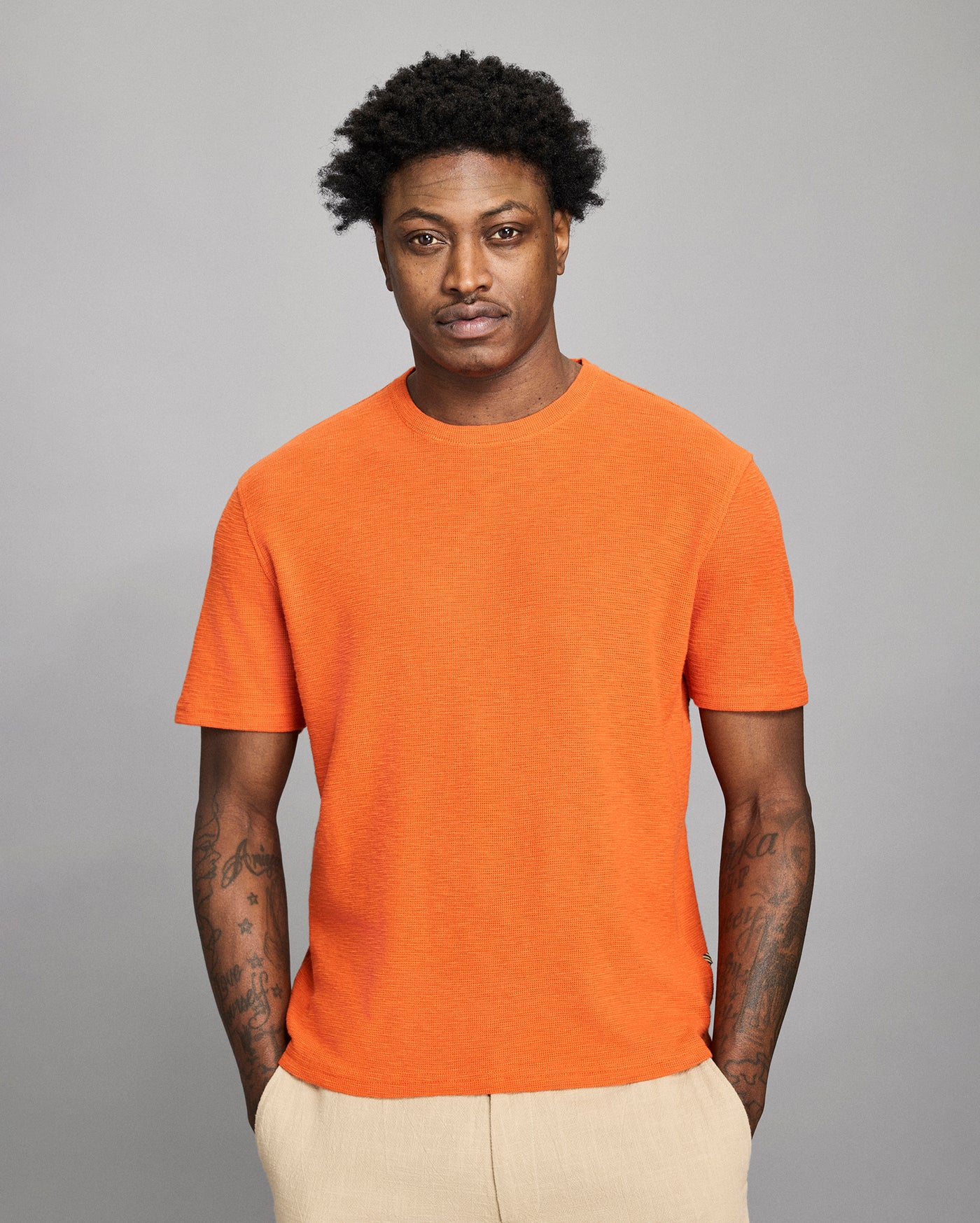 Man wearing an orange t-shirt against a gray background