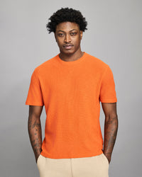 Man wearing an orange t-shirt against a gray background