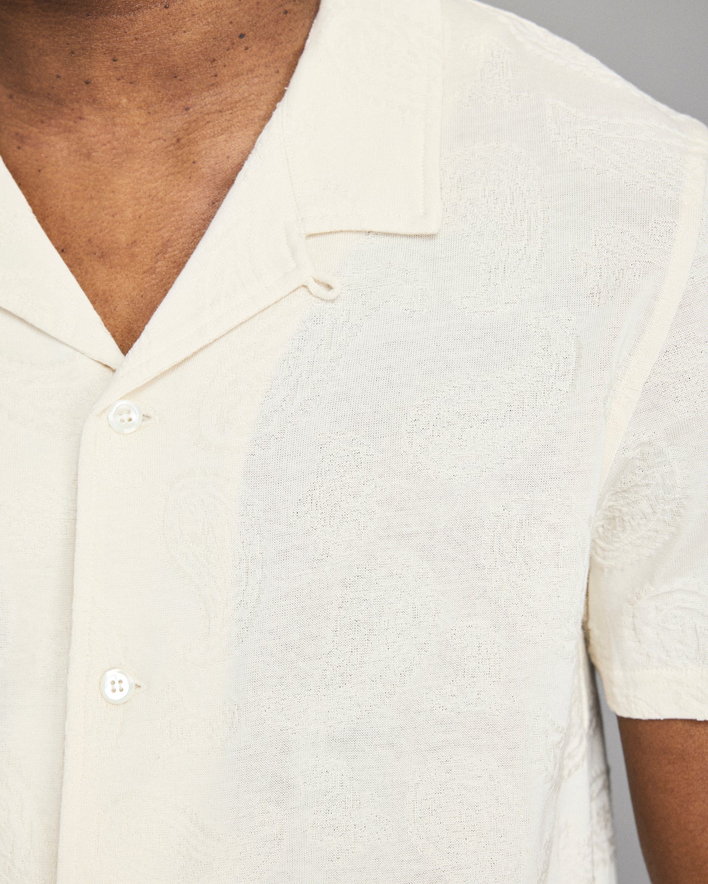 Close-up of a person wearing a white short-sleeve shirt with a collar.